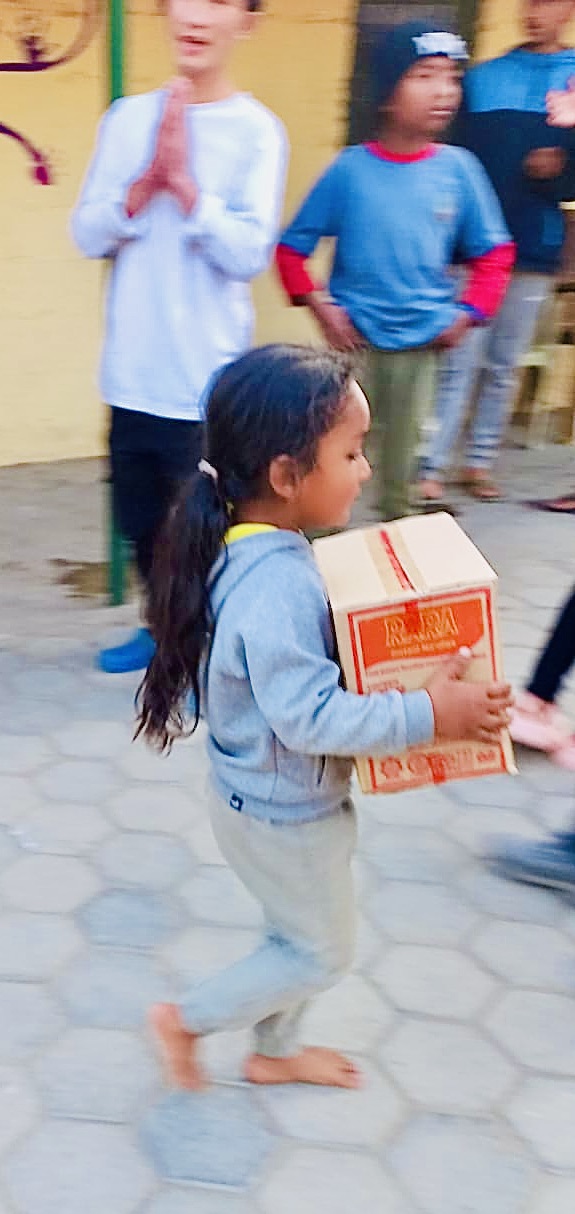 Petite fille qui porte un colis alimentaire